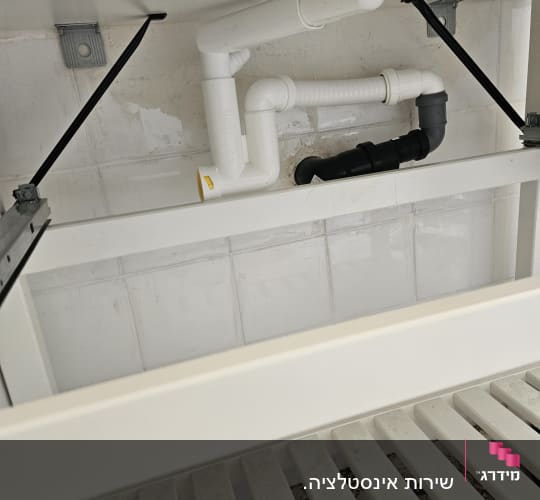 צנרת מתחת לכיור עם חיבורים לבנים ושחורים